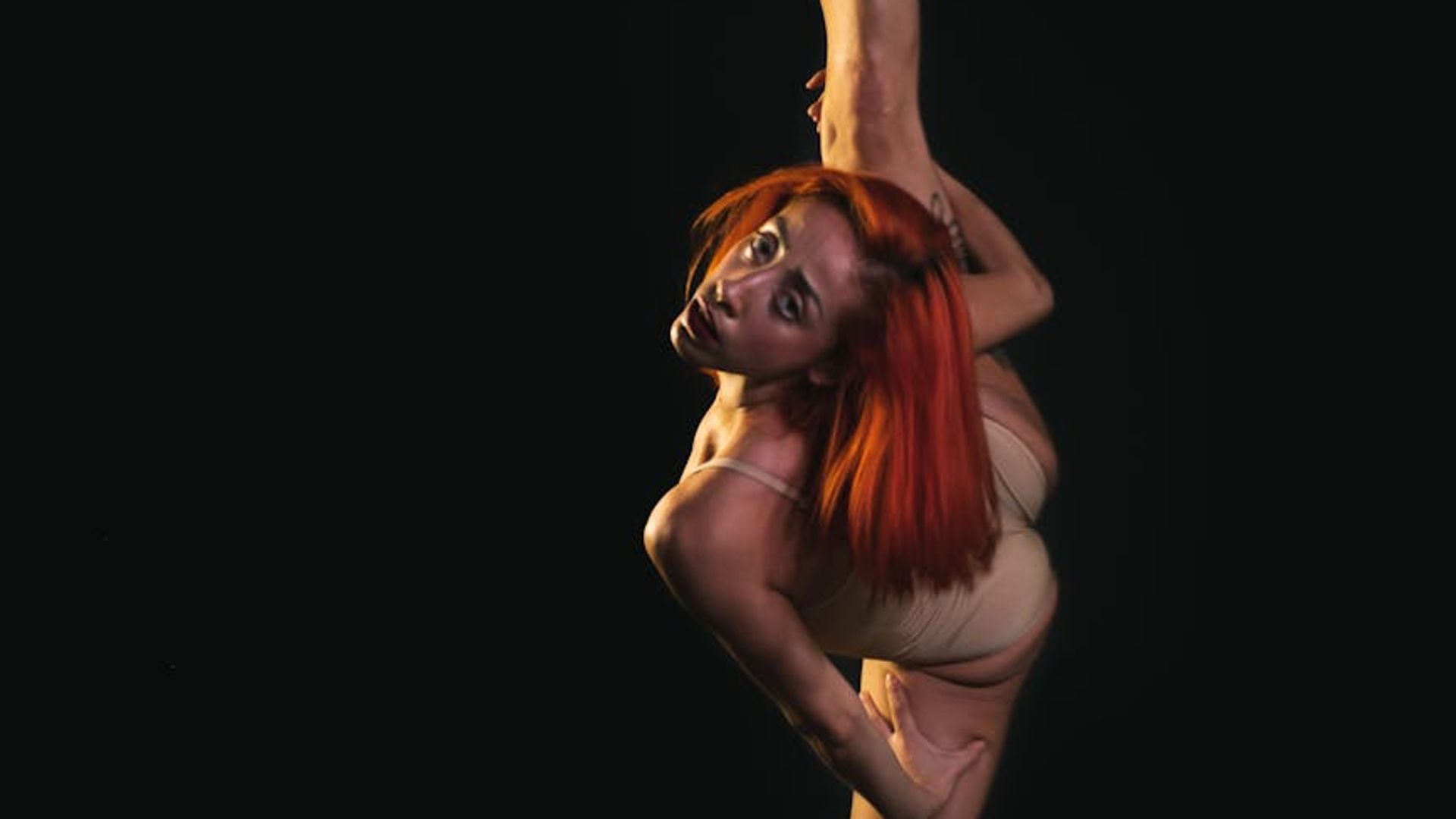 Woman performing graceful movement exercises in a dark studio